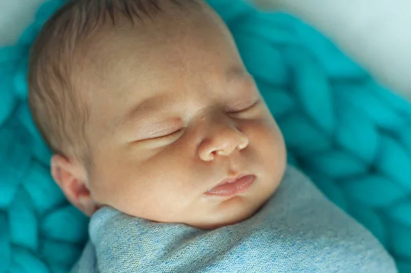 Cute little baby in a blue blanket on the bed at home