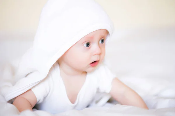 自宅でベッドでお風呂の後に白いタオルでかわいい赤ちゃん — ストック写真