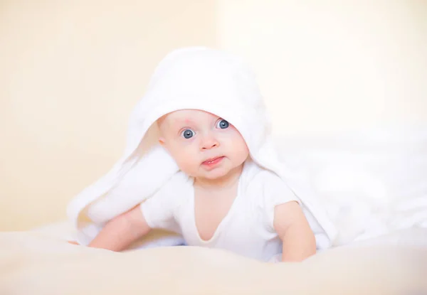 自宅でベッドでお風呂の後に白いタオルでかわいい赤ちゃん — ストック写真