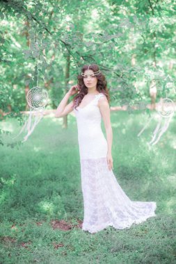Güzel bir saç modeli ile uzun beyaz elbiseli genç çekici kız, bir yaz parkında beyaz rüya yakalayıcılar ile