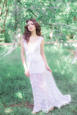 Güzel bir saç modeli ile uzun beyaz elbiseli genç çekici kız, bir yaz parkında beyaz rüya yakalayıcılar ile