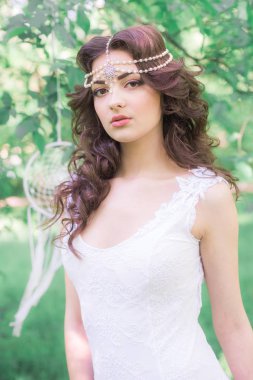 Güzel bir saç modeli ile uzun beyaz elbiseli genç çekici kız, bir yaz parkında beyaz rüya yakalayıcılar ile