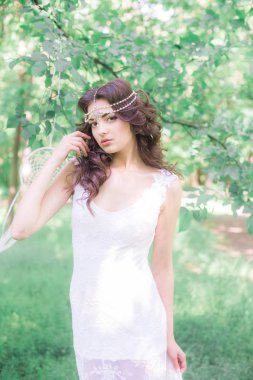 Güzel bir saç modeli ile uzun beyaz elbiseli genç çekici kız, bir yaz parkında beyaz rüya yakalayıcılar ile
