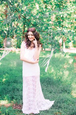 Güzel bir saç modeli ile uzun beyaz elbiseli genç çekici kız, bir yaz parkında beyaz rüya yakalayıcılar ile