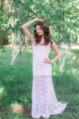 Güzel bir saç modeli ile uzun beyaz elbiseli genç çekici kız, bir yaz parkında beyaz rüya yakalayıcılar ile