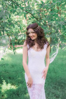 Güzel bir saç modeli ile uzun beyaz elbiseli genç çekici kız, bir yaz parkında beyaz rüya yakalayıcılar ile