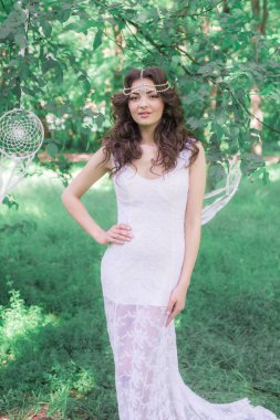 Güzel bir saç modeli ile uzun beyaz elbiseli genç çekici kız, bir yaz parkında beyaz rüya yakalayıcılar ile