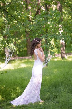 Güzel bir saç modeli ile uzun beyaz elbiseli genç çekici kız, bir yaz parkında beyaz rüya yakalayıcılar ile