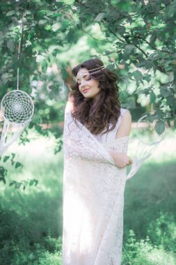 Güzel bir saç modeli ile uzun beyaz elbiseli çekici genç kız, bir yaz parkında beyaz dantel vintage eşarp ile