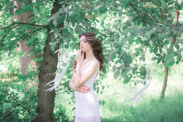 夏の公園で白い夢のキャッチャーと美しい髪型の長い白いドレスを着た若い魅力的な女の子 — ストック写真