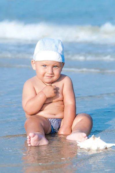 Pequeño Niño Sentado Playa Cerca Del Agua Verano Día Soleado Imagen de stock