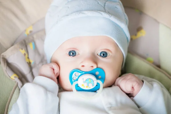 ベッドでリラックスした新生児 子供のための保育園 子供のための織物と寝具 悪いと自宅でカメラを見ておしゃぶりと美しいかわいい青い目の赤ちゃんの子供 — ストック写真