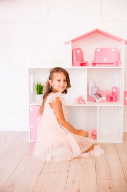 Evde güzel bir elbise sevimli mutlu kız bir dollhouse ve oyuncaklar ile oynar