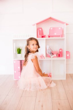 Evde güzel bir elbise sevimli mutlu kız bir dollhouse ve oyuncaklar ile oynar