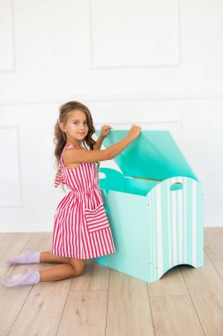 Evde güzel bir elbise sevimli kız dekoratif bir göğüs ve oyuncaklar ile oynar