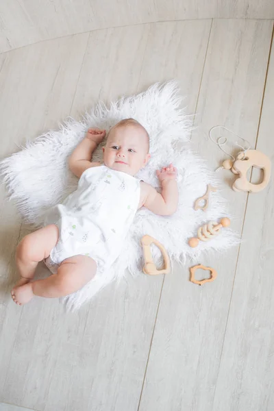 Lindo Bebê Recém Nascido Está Tapete Branco Joga Primeiros Brinquedos — Fotografia de Stock