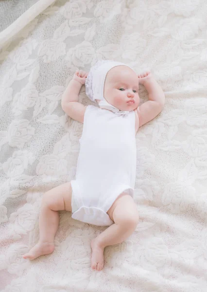 白い服を着たかわいい幼児の赤ちゃんは 自宅で白いベッドの上に横たわっています — ストック写真
