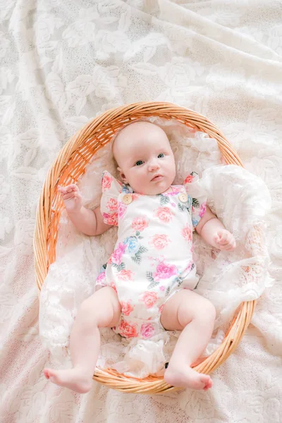 可爱的宝贝婴儿在花卉印花衣服躺在一个柳条篮子在白色的床上在家里 — 图库照片
