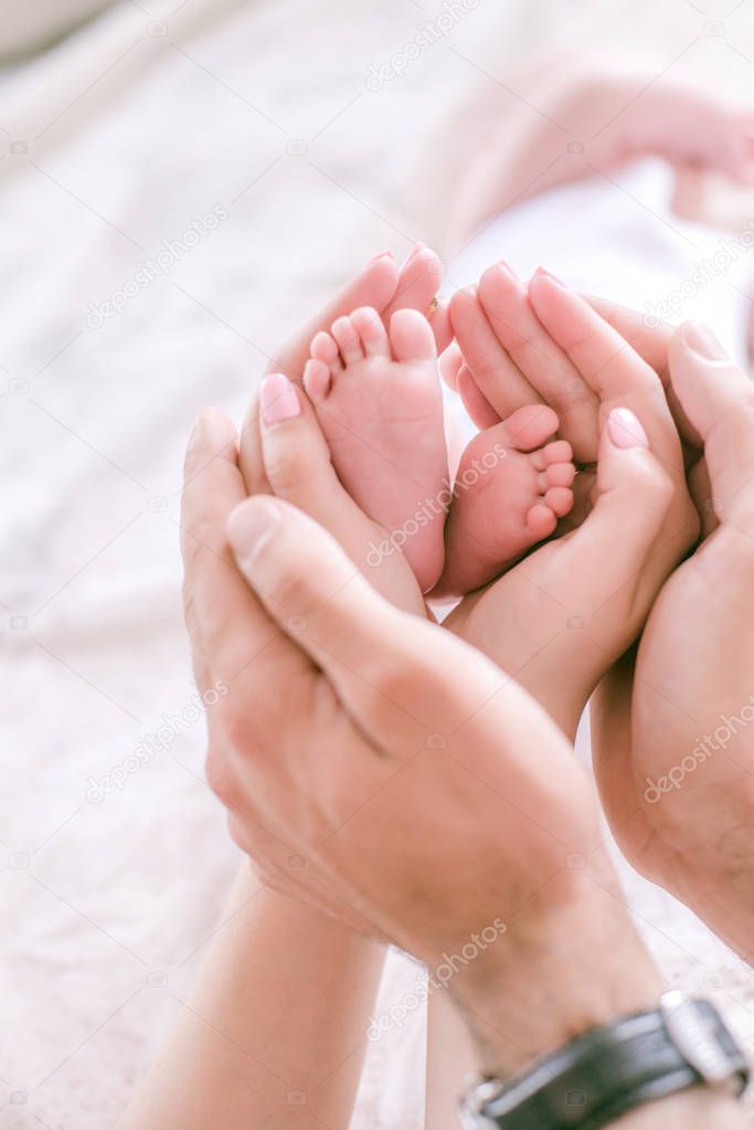 Little baby feet in the hands of parents. Happy motherhood