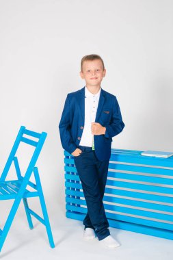 Bir okul çantası ve beyaz bir arka plan üzerinde bir kitap ile şık okul giysileri erkek öğrenci