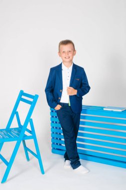 Bir okul çantası ve beyaz bir arka plan üzerinde bir kitap ile şık okul giysileri erkek öğrenci