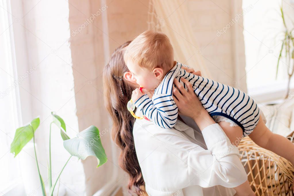 A young mother plays with her little son at home in the bedroom. Happy motherhood