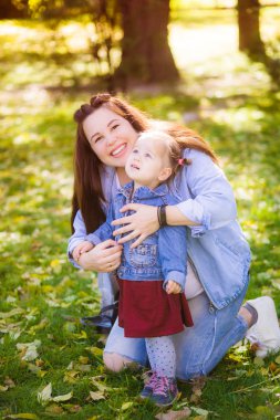Genç hamile bir anne bir sonbahar parkında küçük kızı ile oynar. Mutlu annelik. Mutlu sağlıklı gebelik