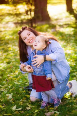 Genç hamile bir anne bir sonbahar parkında küçük kızı ile oynar. Mutlu annelik. Mutlu sağlıklı gebelik