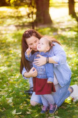 Genç hamile bir anne bir sonbahar parkında küçük kızı ile oynar. Mutlu annelik. Mutlu sağlıklı gebelik