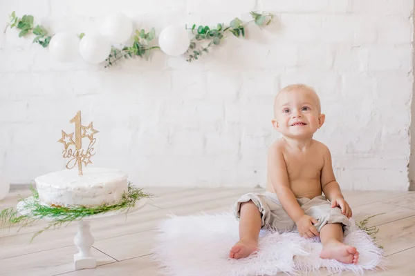 可爱的小男孩在他的第一个生日与节日蛋糕和装饰与白色的气球和枝花的紫杉 生锈的第一个生日派对 — 图库照片
