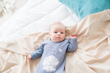 Küçük sevimli bebek yatakta evde yatıyor. Mutlu çocukluk