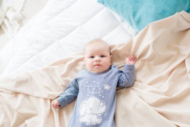 Küçük sevimli bebek yatakta evde yatıyor. Mutlu çocukluk