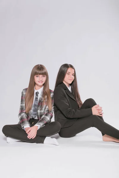 Twee Leuke Meisjes Schoolmeisjes Een Trendy Schooluniform Een Witte Achtergrond — Stockfoto