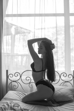 Bir yatakta siyah dantel iç çamaşırı uzun koyu saçlı genç çekici kadın. Genç bir kızın Boudoir fotoğrafı
