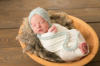 Beyaz bir battaniye ahşap bir sepet içinde mavi örme şapka sevimli yenidoğan bebek