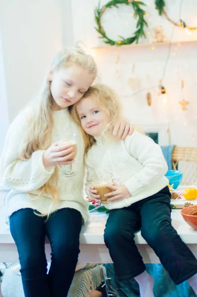 Dvě Roztomilá Sestřičky Blonďatými Kudrnatými Vlasy Vánočním Stole Pijou Kakao — Stock fotografie