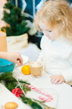 Noel masasında sarışın kıvırcık saçlı iki sevimli kız kız kız kakao içmek ve zencefilli kurabiye yemek. Noel ruh hali