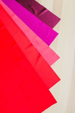 Ahşap arka planda parlak renkli kumaş kesikleri. Dikiş için kumaşlar. Dikiş malzemeleri