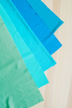 Ahşap arka planda parlak renkli kumaş kesikleri. Dikiş için kumaşlar. Dikiş malzemeleri