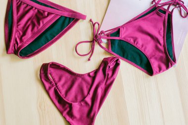 Ahşap arka planda parlak moda bikiniler ve moda dergileri. Modaya uygun plaj giysileri ve aksesuarları..