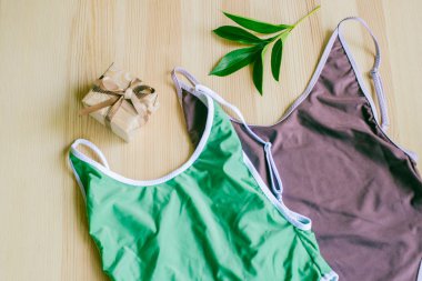 Tropikal yeşil yapraklı, ahşap bir arka planda parlak moda bikini. Modaya uygun plaj kıyafeti..