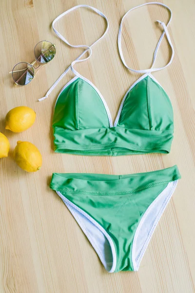 色彩艳丽的比基尼 木制背景 黄色柠檬和热带绿叶 时髦的泳衣 — 图库照片