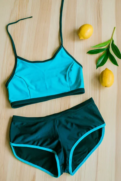色彩艳丽的比基尼 木制背景 黄色柠檬和热带绿叶 时髦的泳衣 — 图库照片