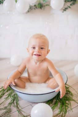 Tatlı küçük çocuk sabunlu su ve sabun köpüğüyle havuza su sıçratıyor. Sağlıklı çocukluk