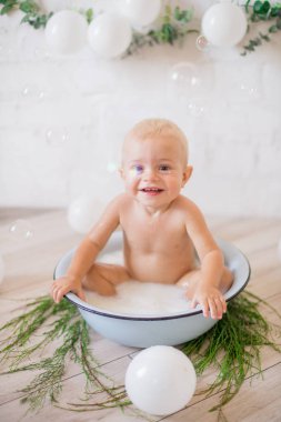 Tatlı küçük çocuk sabunlu su ve sabun köpüğüyle havuza su sıçratıyor. Sağlıklı çocukluk