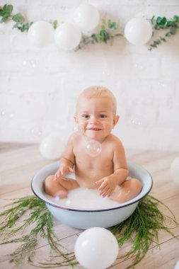 Tatlı küçük çocuk sabunlu su ve sabun köpüğüyle havuza su sıçratıyor. Sağlıklı çocukluk