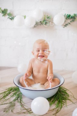 Tatlı küçük çocuk sabunlu su ve sabun köpüğüyle havuza su sıçratıyor. Sağlıklı çocukluk