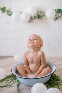 Tatlı küçük çocuk sabunlu su ve sabun köpüğüyle havuza su sıçratıyor. Sağlıklı çocukluk