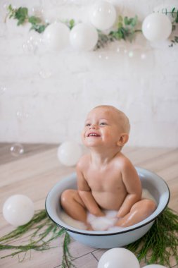 Tatlı küçük çocuk sabunlu su ve sabun köpüğüyle havuza su sıçratıyor. Sağlıklı çocukluk