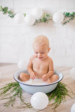 Tatlı küçük çocuk sabunlu su ve sabun köpüğüyle havuza su sıçratıyor. Sağlıklı çocukluk